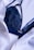 A dark blue lace bra is partially covered by a white button-up shirt. The fabric of both the bra and the shirt appears to be of fine texture, with the bra having intricate lace details and the shirt having a smooth, slightly crinkled texture.