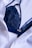 A dark blue lace bra is partially covered by a white button-up shirt. The fabric of both the bra and the shirt appears to be of fine texture, with the bra having intricate lace details and the shirt having a smooth, slightly crinkled texture.