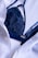 A dark blue lace bra is partially covered by a white button-up shirt. The fabric of both the bra and the shirt appears to be of fine texture, with the bra having intricate lace details and the shirt having a smooth, slightly crinkled texture.