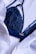 A dark blue lace bra is partially covered by a white button-up shirt. The fabric of both the bra and the shirt appears to be of fine texture, with the bra having intricate lace details and the shirt having a smooth, slightly crinkled texture.
