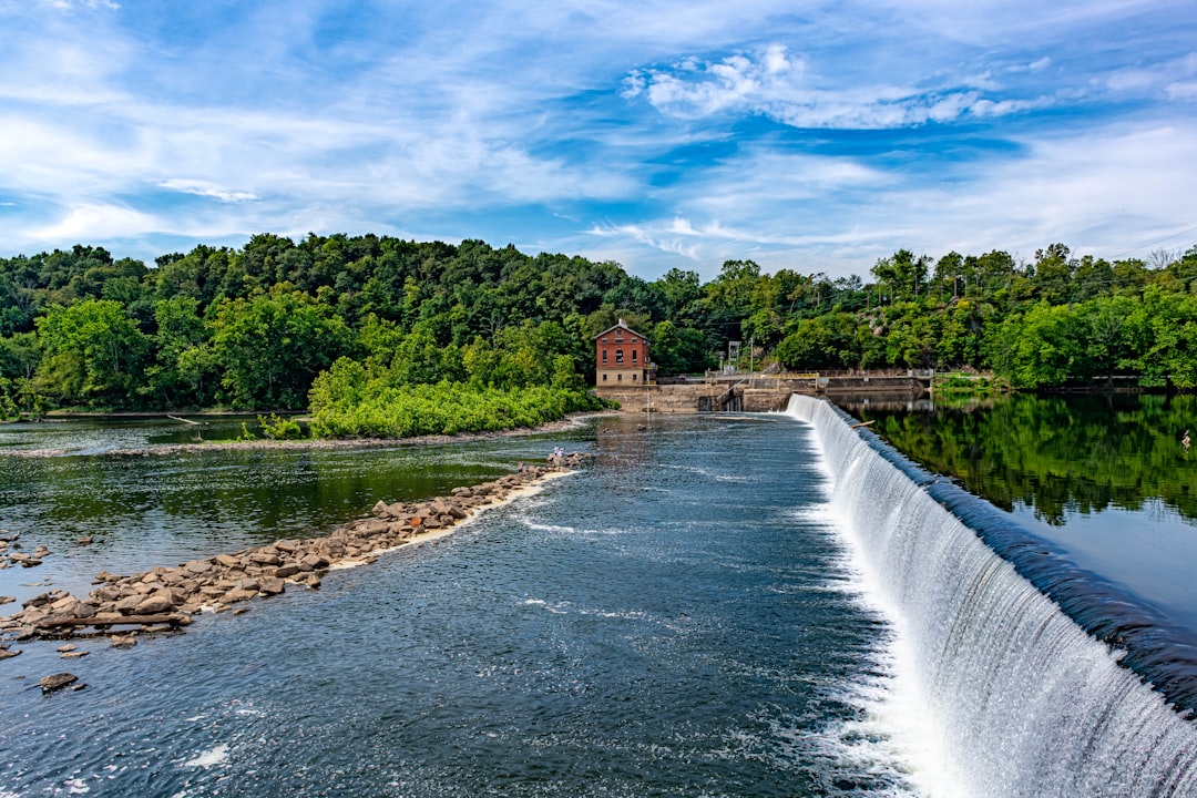 water falls near green trees under blue sky during daytime