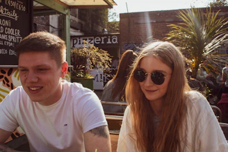 Couple enjoying a sunny outdoor café with yellow accents in the background.
