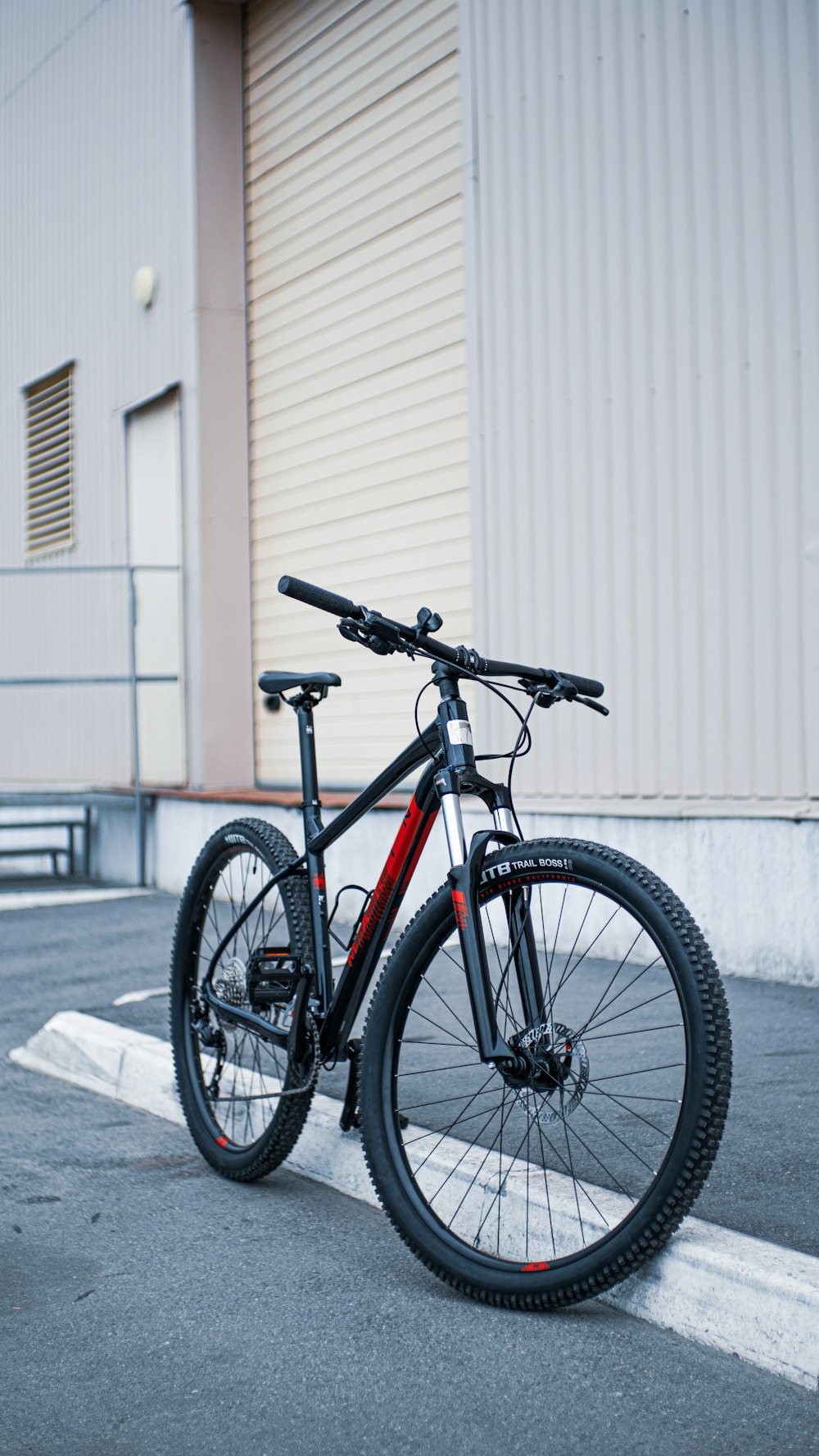 black and orange road bike parked beside white wall