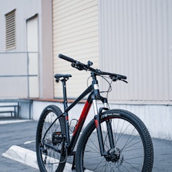 black and orange road bike parked beside white wall