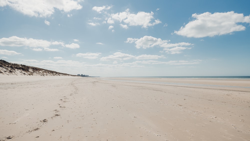 praia de areia branca sob o céu azul durante o dia