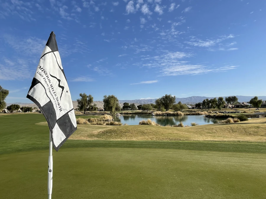 Golf flag on a green beside a lake under a blue sky