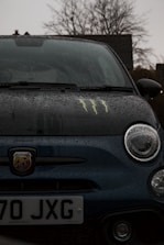 A close-up of a car with rain droplets, symbolizing protection against weather damage.