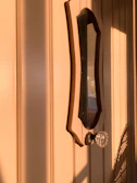 A sturdy vintage door with classic iron handles bathed in warm sunlight.