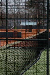 Tennis court featuring tightly woven protective mesh nets along the sides.