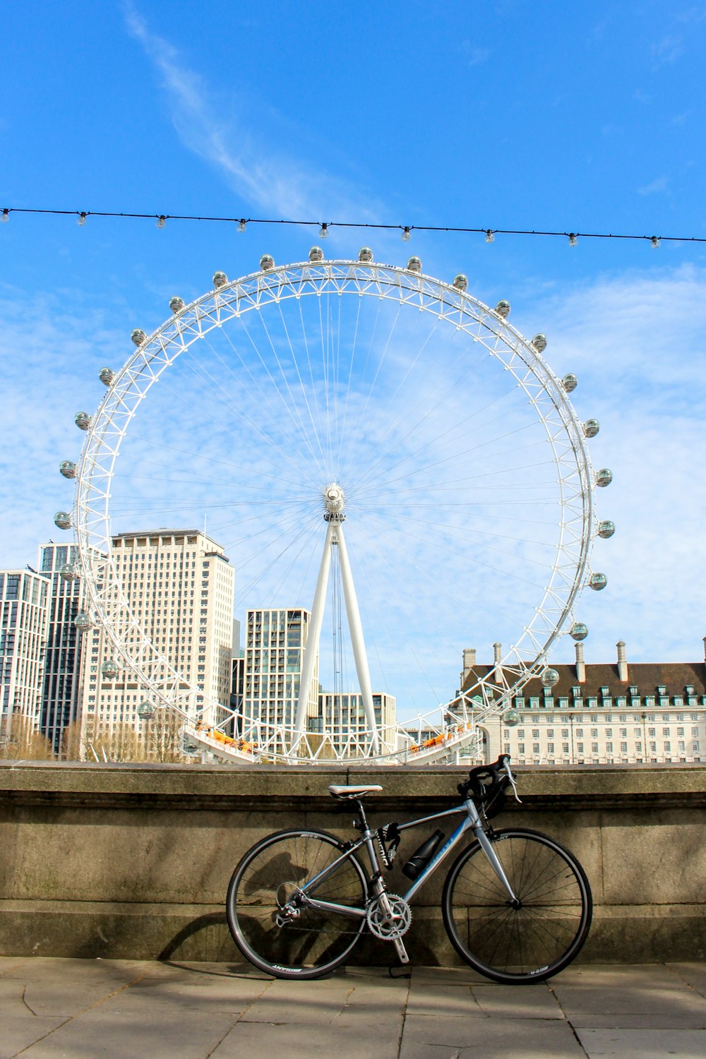 bicycle parked beside concrete wall near white high rise building during daytime