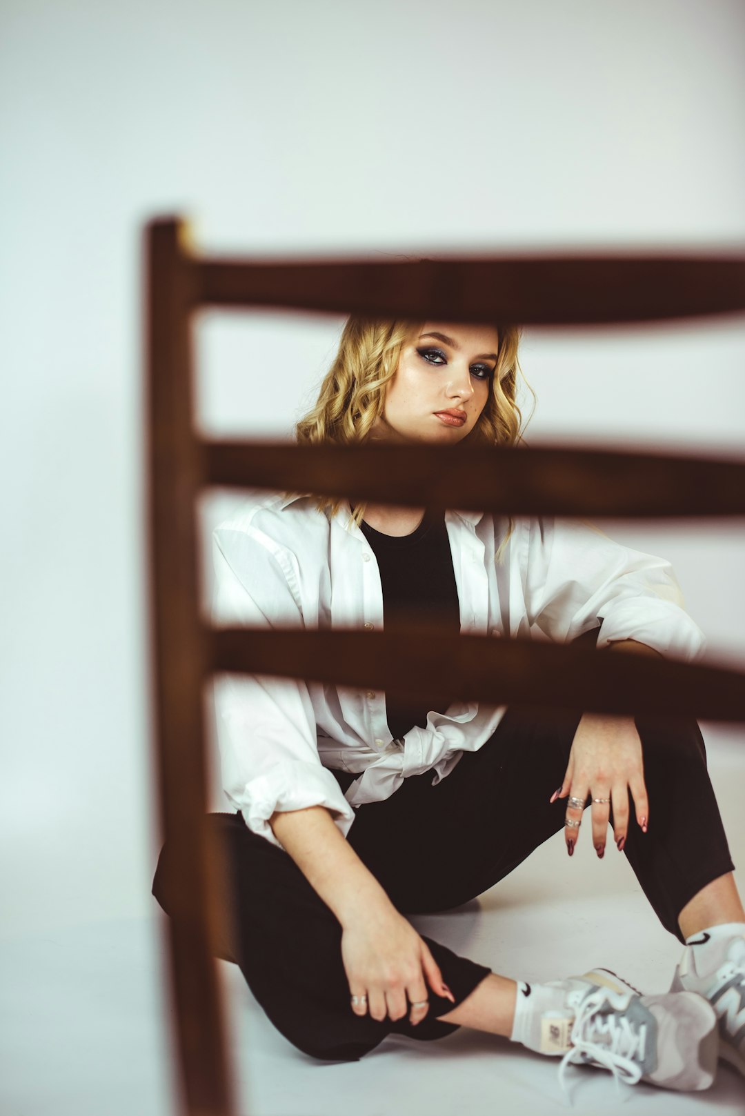 girl in white shirt and black skirt sitting on brown wooden chair