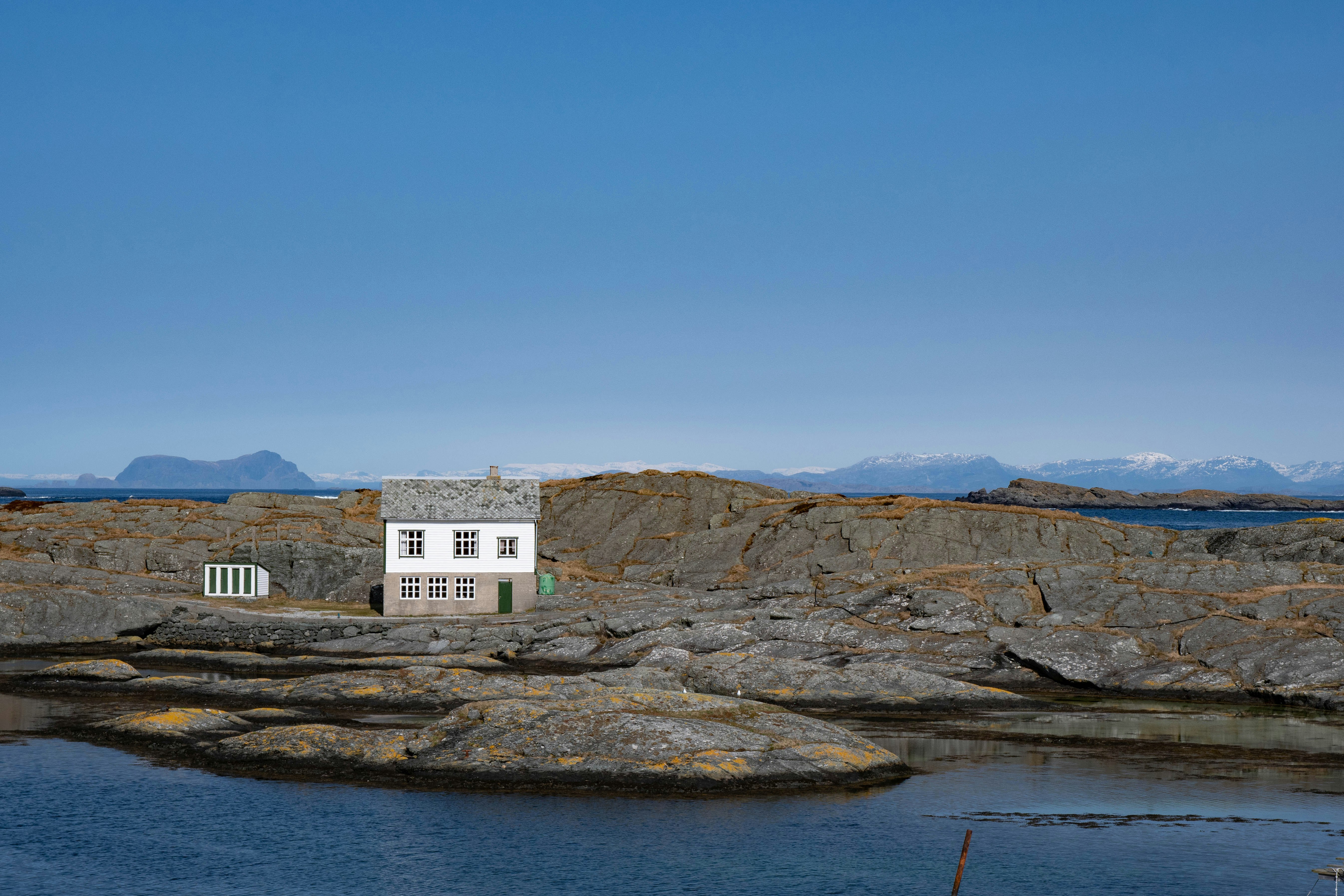 white concrete building on brown rocky mountain beside body of water during daytime