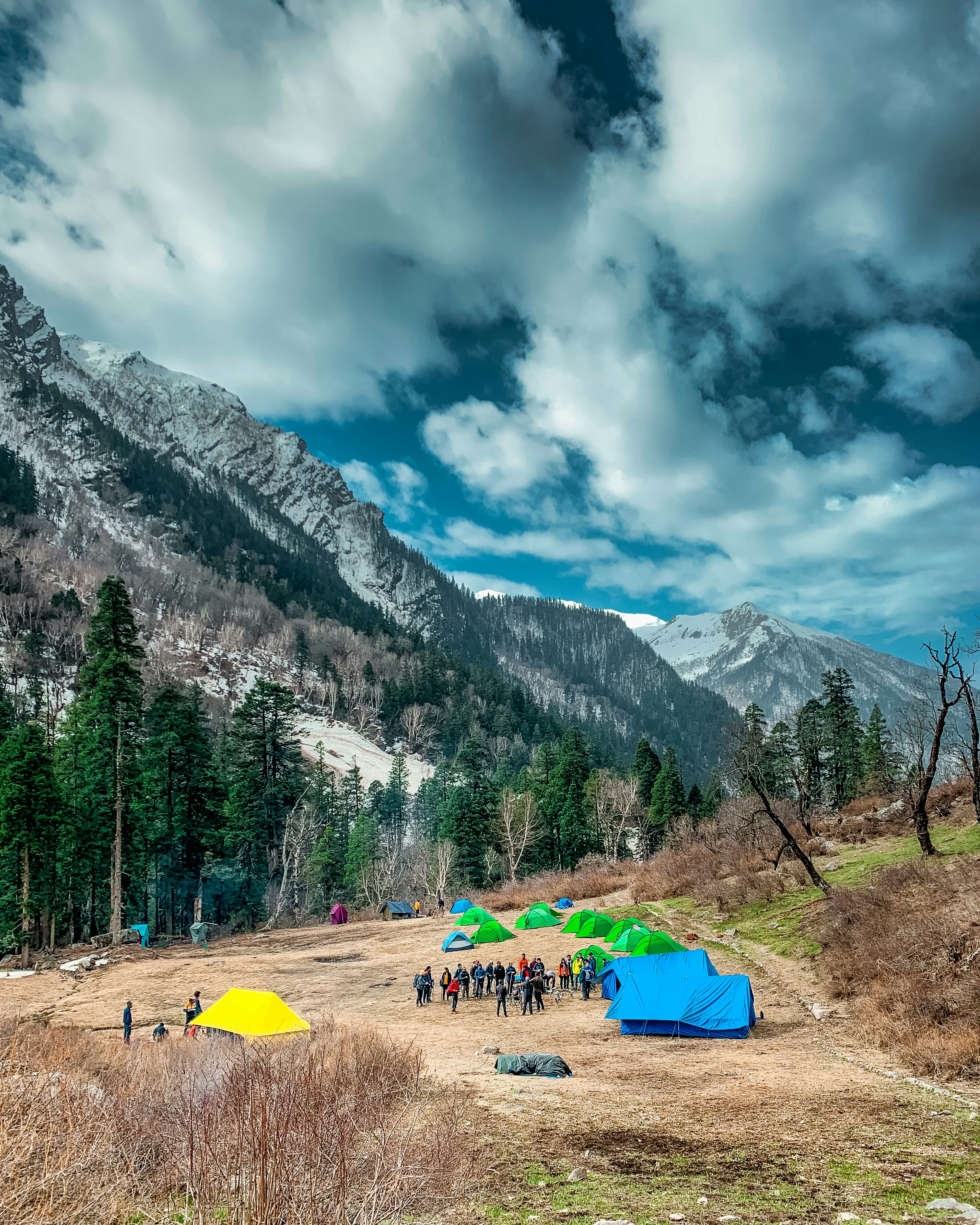 green and yellow tent near green trees and mountain under white clouds and blue sky during