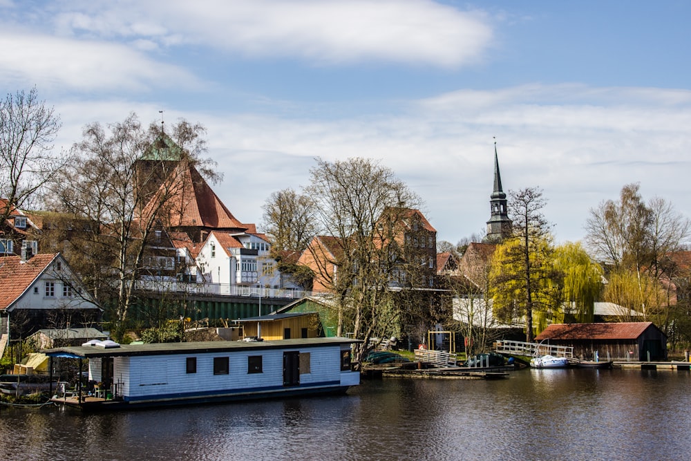 Weißes und grünes Boot auf dem Fluss in der Nähe von braunem und weißem Betongebäude tagsüber