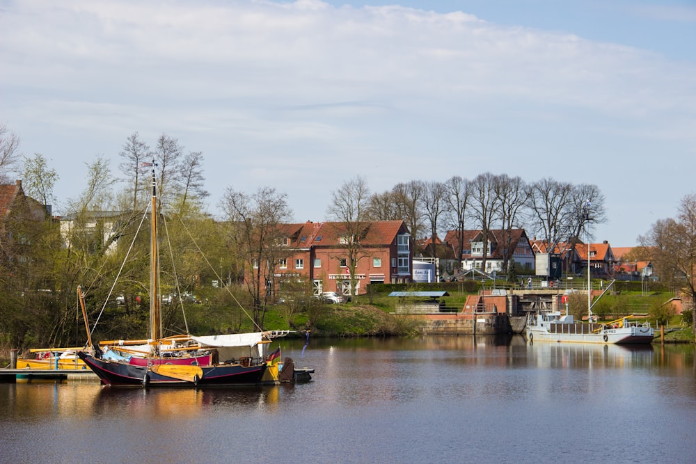 Braunes und weißes Boot auf dem Fluss in der Nähe von Häusern während des Tages