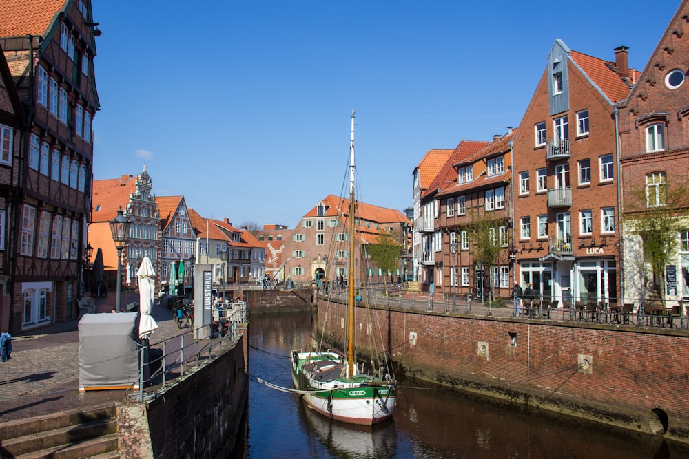 blau-weißes Boot tagsüber auf dem Wasser in der Nähe des braunen Betongebäudes