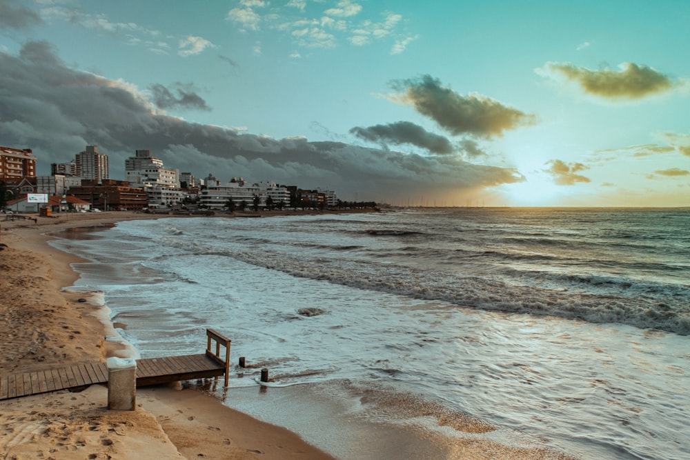 white wooden bench on beach shore during daytime