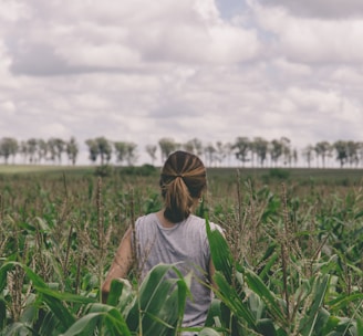 woman in gray shirt standing on green grass field during daytime