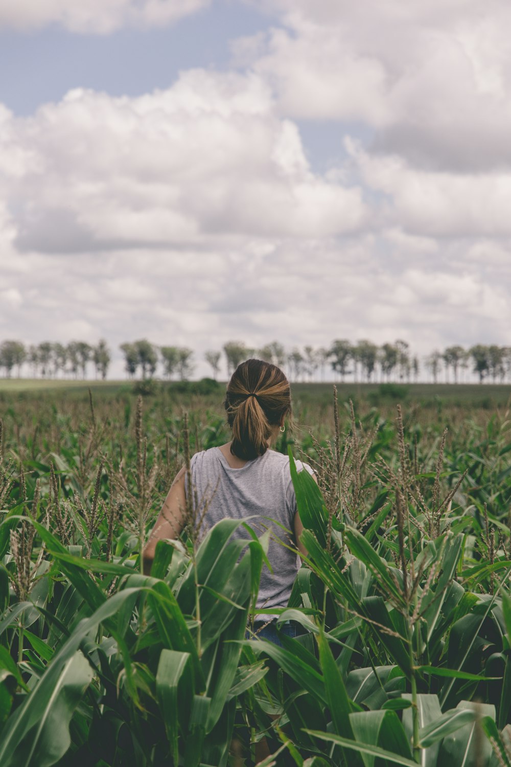 donna in camicia grigia in piedi sul campo di erba verde durante il giorno