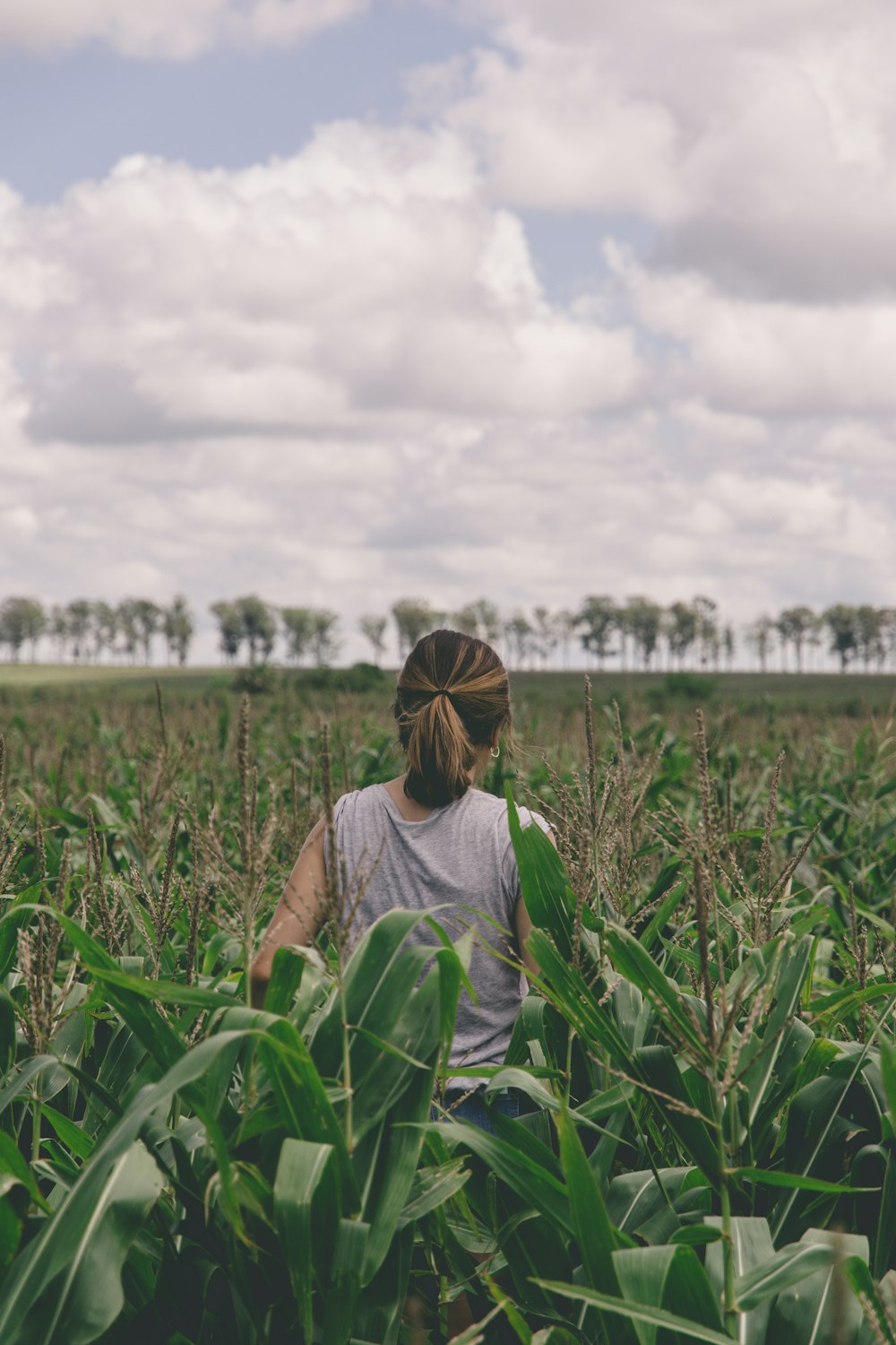 woman in gray shirt standing on green grass field during daytime