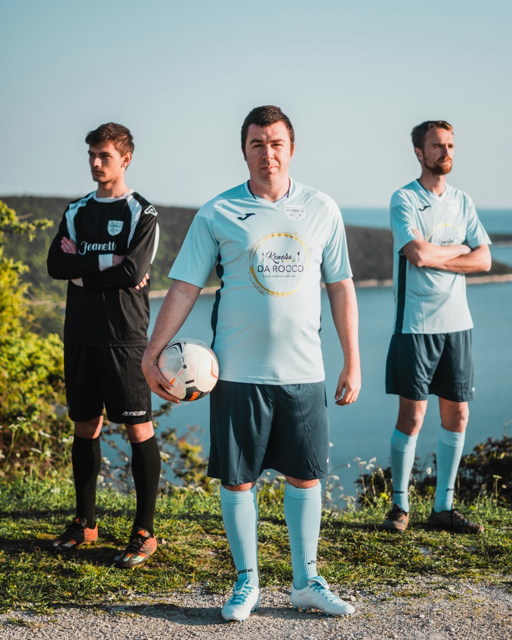 3 men standing on green grass field during daytime