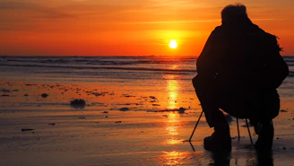 silhouette of man standing on beach during sunset