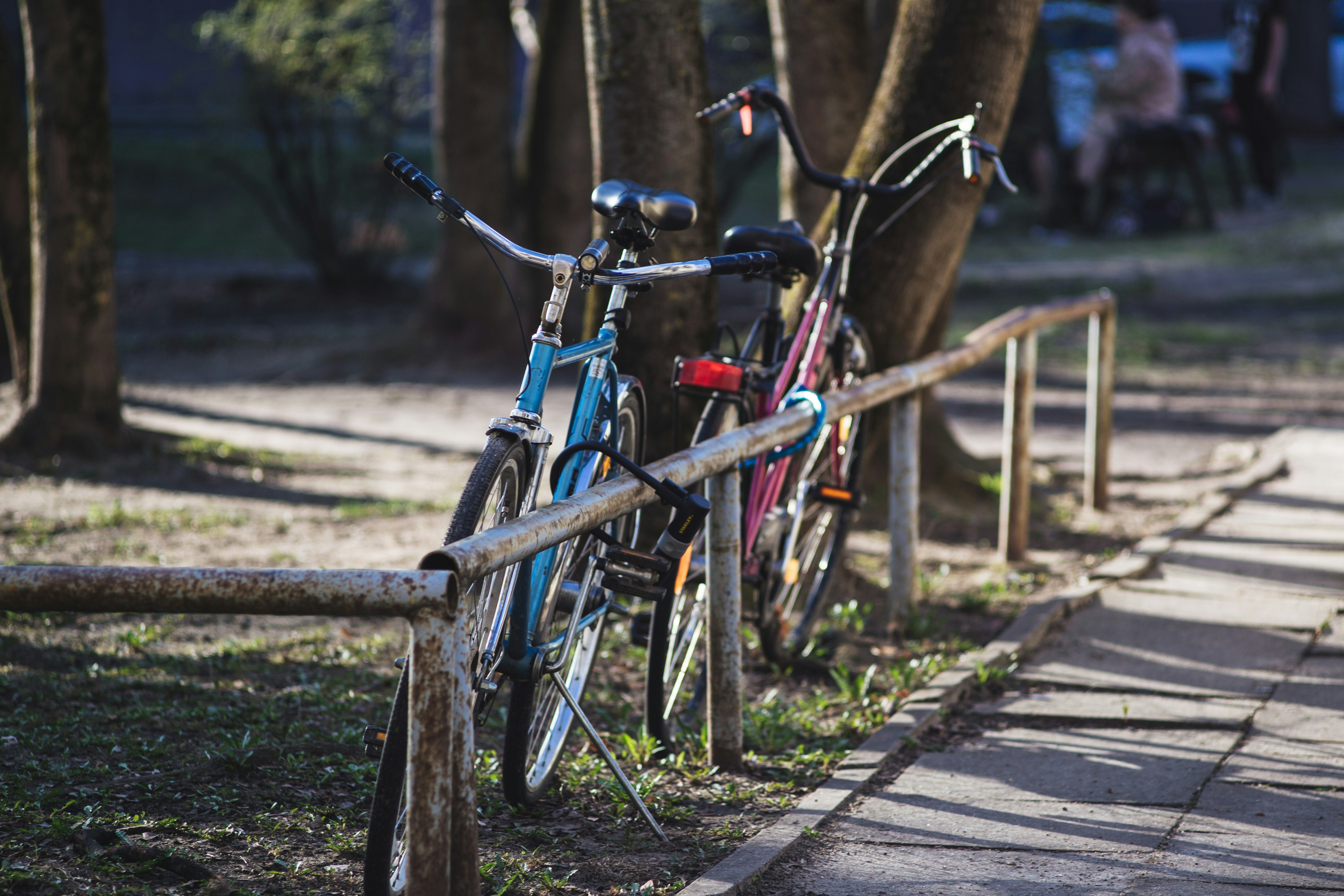 blue and black city bikes parked on brown wooden fence during daytime