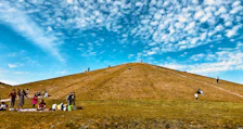 Guests enjoying a picnic on a sunny grassy hill overlooking the mountains.