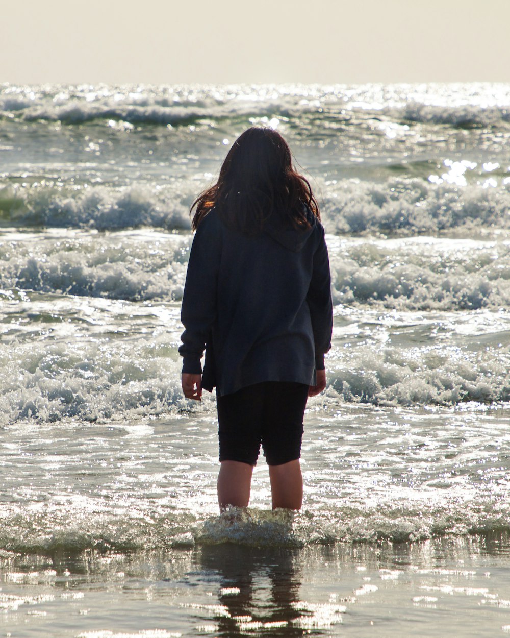 woman in black jacket standing on water during daytime