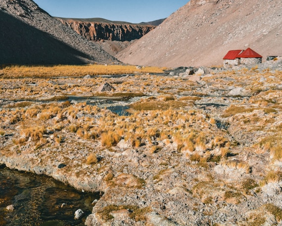 red and brown house near river and mountains during daytime