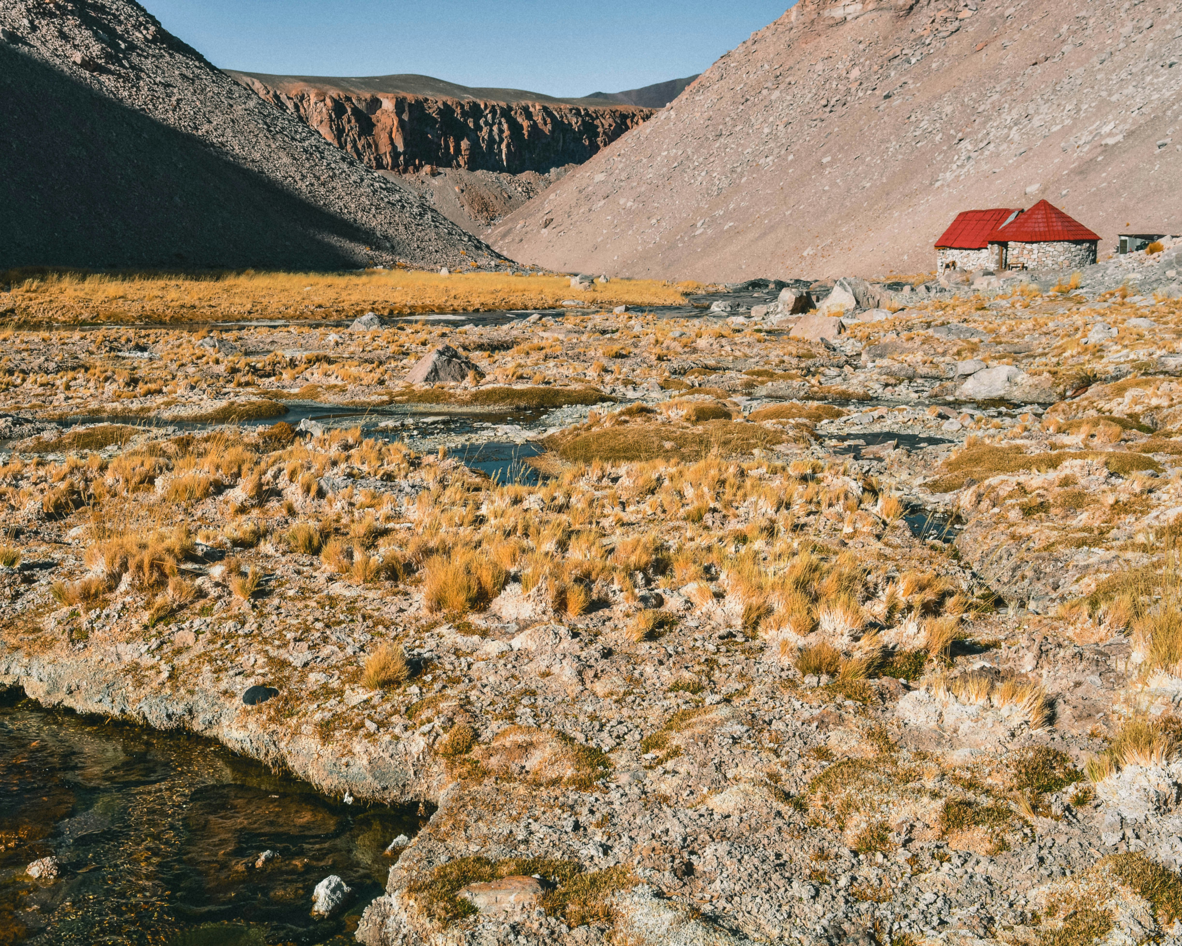 red and brown house near river and mountains during daytime