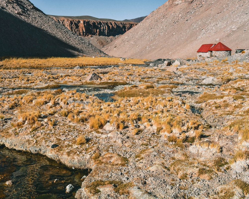 Casa rossa e marrone vicino al fiume e alle montagne durante il giorno