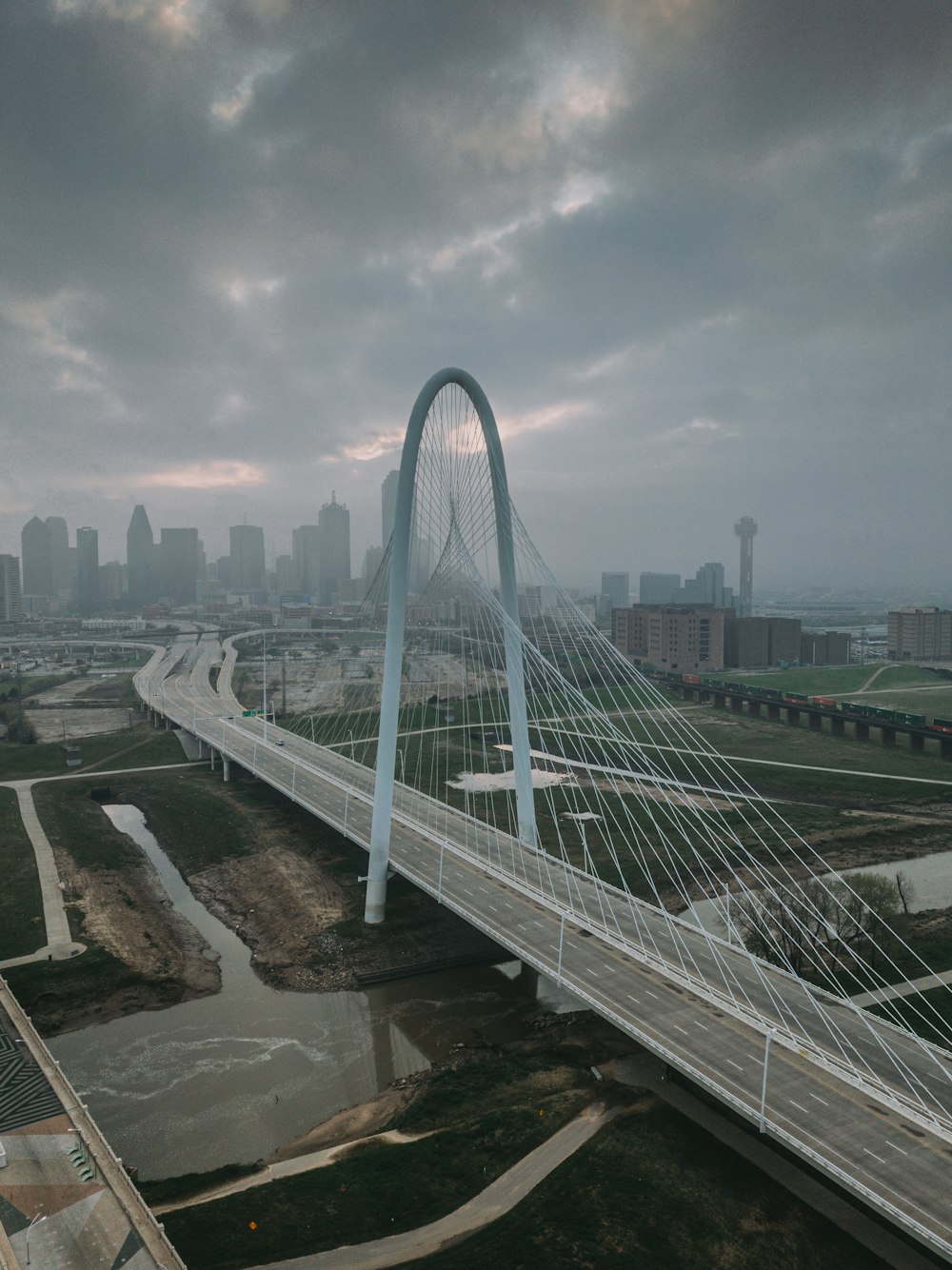 white bridge over city buildings under cloudy sky during daytime