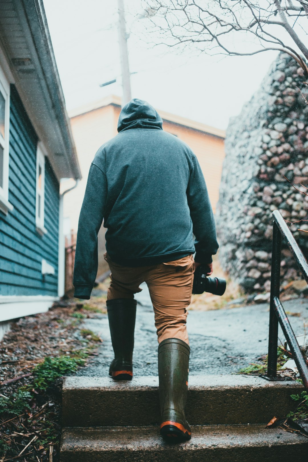 man in gray hoodie and brown pants standing on black metal railings during daytime