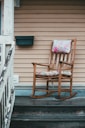 brown wooden rocking chair near white wooden fence