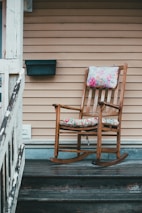 brown wooden rocking chair near white wooden fence