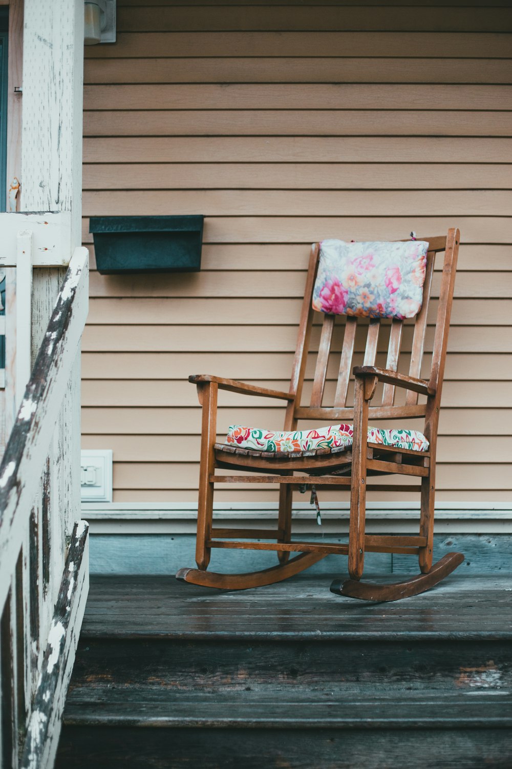 brown wooden rocking chair near white wooden fence