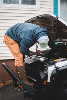 man in blue long sleeve shirt and brown pants standing beside black car