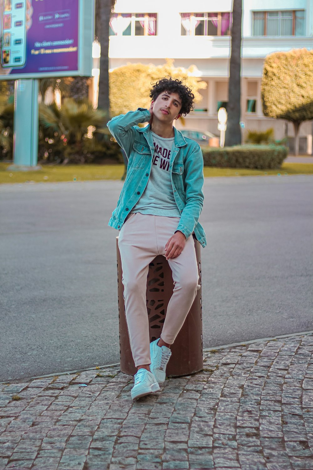 woman in blue denim jacket and brown pants standing on sidewalk during daytime