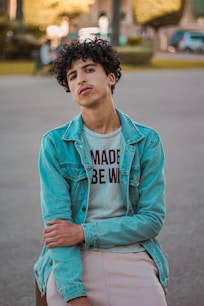 man in blue denim jacket standing on road during daytime