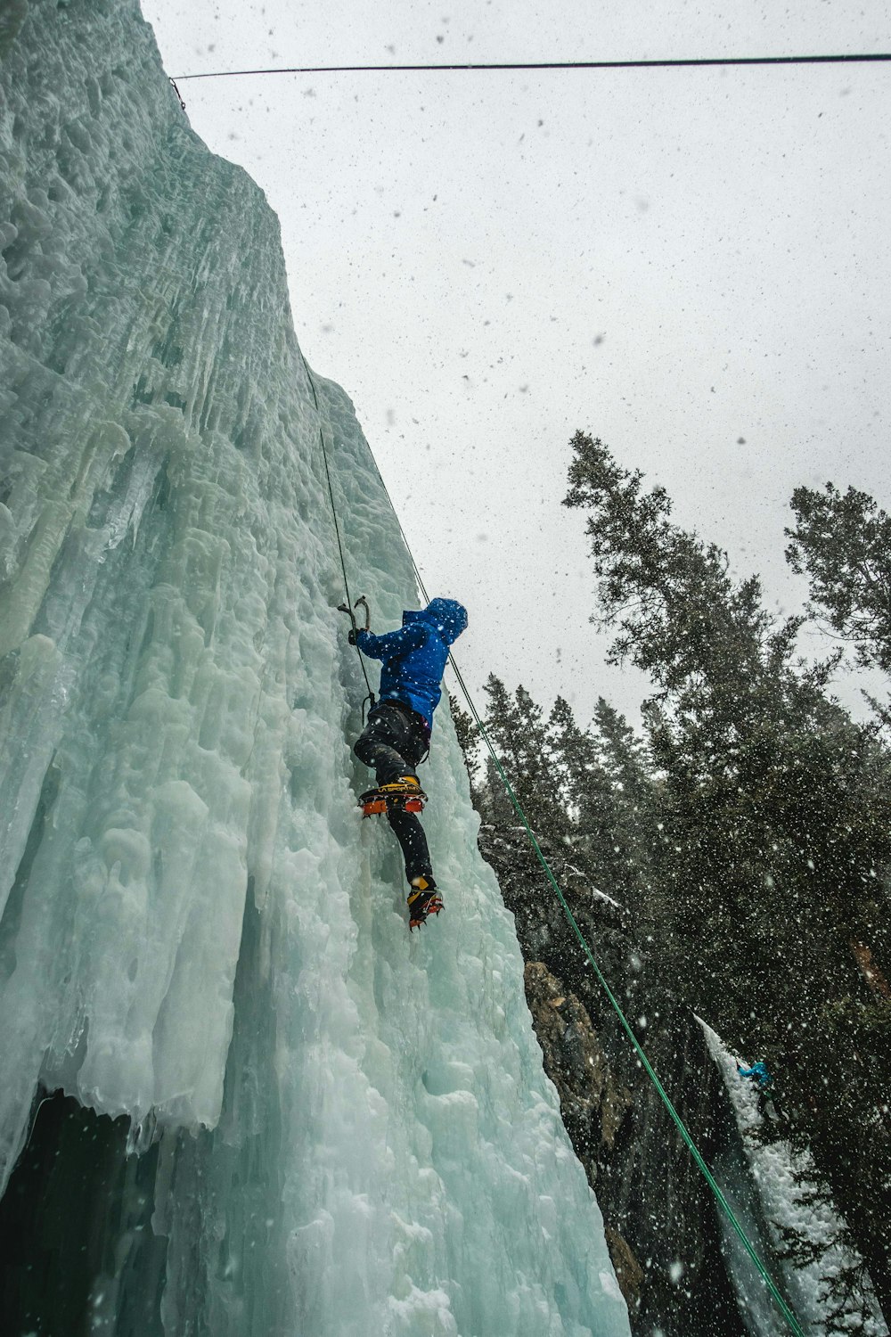 man in blue jacket and black pants climbing on snow covered mountain during daytime