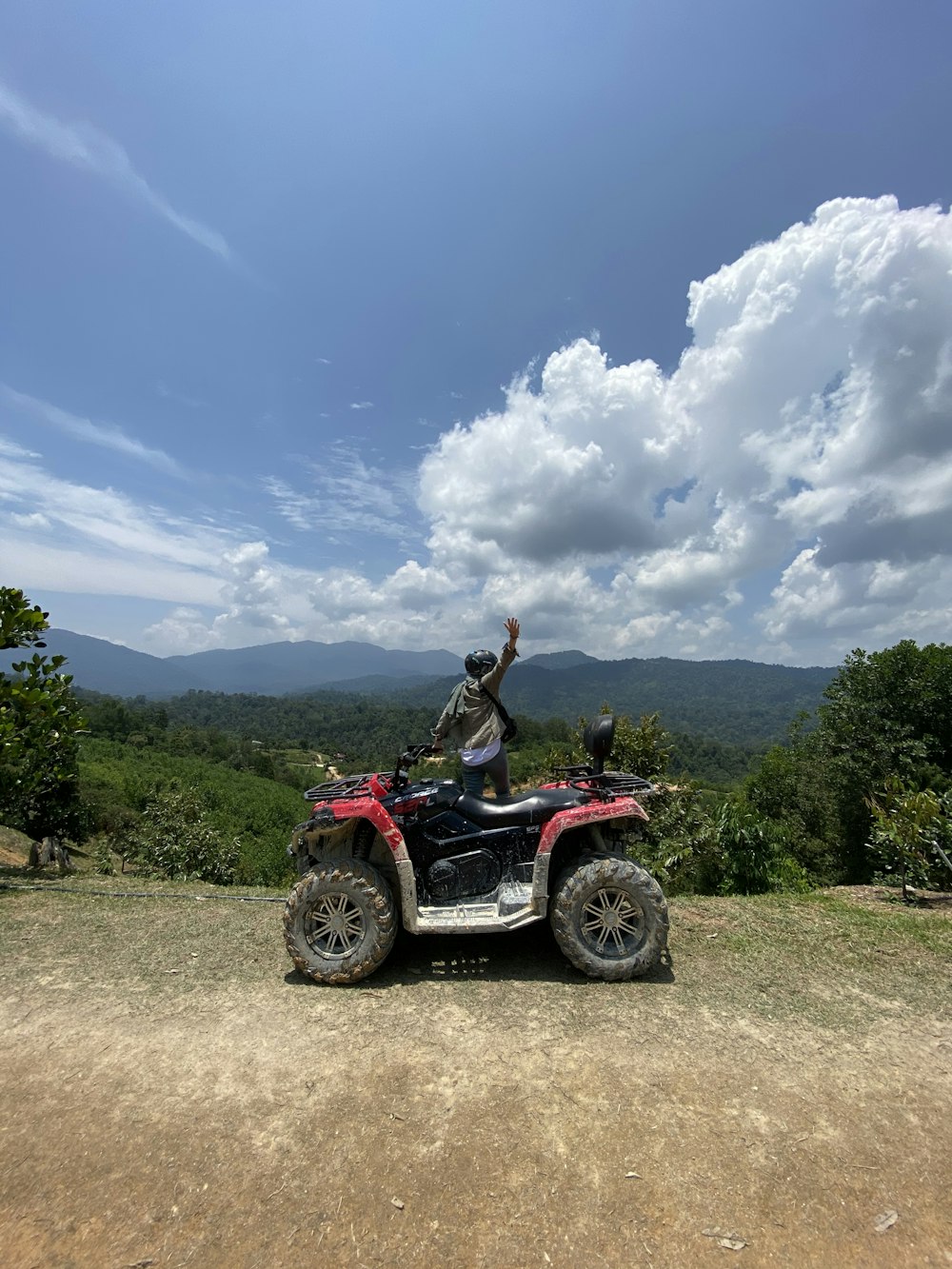 昼間の未舗装の道路で赤と黒のATVを着た女性