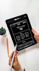 person holding black ipad with green plant