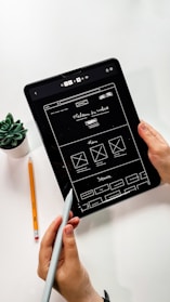 person holding black ipad with green plant