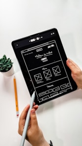 person holding black ipad with green plant