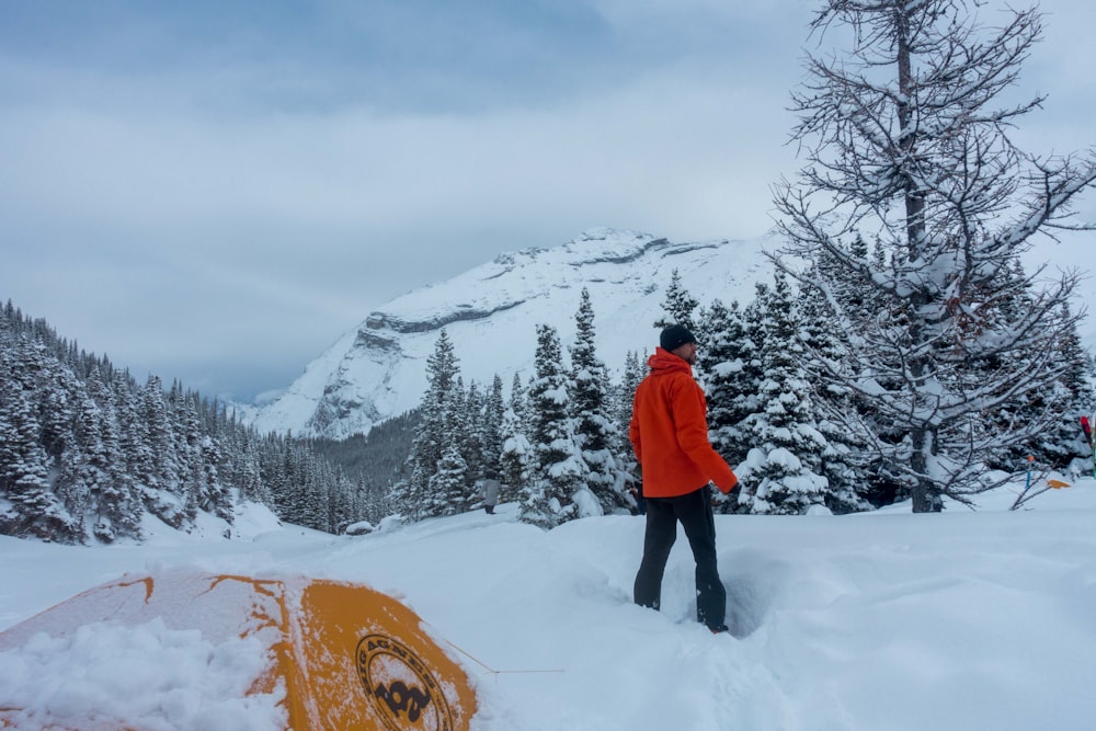 person in red jacket standing on snow covered ground during daytime