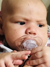 Close-up of a smooth, honey-colored natural latex pacifier resting gently on soft fabric.