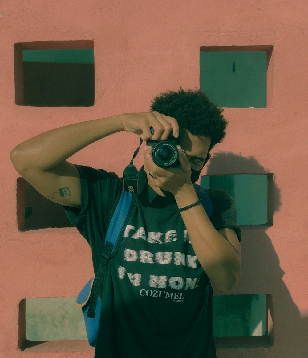 man in blue and white adidas tank top holding black camera