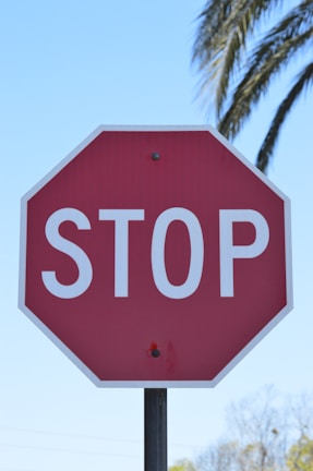 Close-up of a traffic controller holding a stop sign against a clear blue sky.