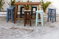 Colorful plastic patio stools arranged around a rustic wooden table, inviting casual gatherings.